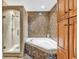 Luxurious bathroom with a soaking tub, granite wall accents, a separate glass shower, and rich wooden cabinetry at 1352 Villa Marbella Ct. # 1-104, Myrtle Beach, SC 29572