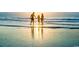 A Gathering holds hands wading in the water at sunset on the beach at 1352 Villa Marbella Ct. # 1-104, Myrtle Beach, SC 29572