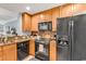 A modern kitchen featuring a black refrigerator, range, and microwave set against granite countertops and wooden cabinetry at 1352 Villa Marbella Ct. # 1-104, Myrtle Beach, SC 29572