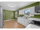 Kitchen with olive green walls and white cabinets featuring a stainless sink, appliances, and wood grain floors at 140 Flag Patch Rd., Loris, SC 29569