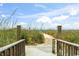 Beach access path through grassy dunes, featuring showers and a wooden walkway to the sandy shore on a sunny day at 1425 S Ocean Blvd. # 8-B, North Myrtle Beach, SC 29582