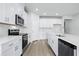 Bright kitchen features white cabinets, stainless steel appliances, quartz countertops and wood-look flooring at 2024 Copper Creek Loop, Longs, SC 29568