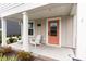 Inviting front porch featuring a cozy seating area, a bright door, and manicured landscaping at 9000 Mabel Ct., Longs, SC 29568