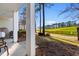 Covered patio with seating overlooking the green golf course with a wooden fence and mature trees at 100 Cypress Point Ct. # 105, Myrtle Beach, SC 29579