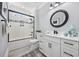 Bright bathroom featuring a modern vanity, round mirror, and tub-shower combination with glass door at 1109 Wigeon Dr., Conway, SC 29526