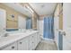 Well-lit bathroom featuring a double sink vanity and shower with blue curtain at 1450 Portrait Circle # 1450, Myrtle Beach, SC 29577