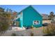 View of the back of a two-story turquoise home with a white fence, patio furniture, and a well-maintained yard at 1607 Havens Dr., North Myrtle Beach, SC 29582