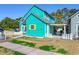 Attractive turquoise home with a cozy front yard, a white picket fence, and a charming beachside aesthetic at 1607 Havens Dr., North Myrtle Beach, SC 29582