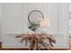 Entryway with decorative table and vases with greenery, round mirror and wainscotting along the walls at 201 Broad St., Georgetown, SC 29440