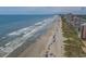 Aerial view of a sandy beach with clear ocean water, umbrellas and people enjoying sunny day at 218 Landing Rd. # G, North Myrtle Beach, SC 29582