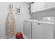 Bright laundry room featuring a washer, dryer, ironing board, upper cabinets, and tile flooring at 2241 Waterview Dr. # 527, North Myrtle Beach, SC 29582