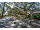 Mature trees casting shadows on a driveway next to a single-story home with brick accents at 304 Queens Rd., Myrtle Beach, SC 29572