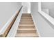 Carpeted staircase featuring a wooden handrail in a brightly lit home at 327 Sandridgebury Dr. # 72, Little River, SC 29566