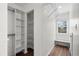 Bright walk-in closet with white shelves, drawers, and wood-look floors with a window and bench at 4350 Goude St., Murrells Inlet, SC 29576