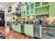 Kitchenette with green cabinets, stainless appliances, wine rack, and brick backsplash detail at 638 S Waccamaw Dr., Murrells Inlet, SC 29576