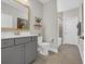 Bathroom with a gray vanity, white toilet, gold framed mirror, and decorative plant on a floating shelf at 7322 Sarteano Dr., Myrtle Beach, SC 29572