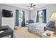 Well-lit bedroom with a large bed, blue curtains, and comfortable seating area at 7609 Driftwood Dr., Myrtle Beach, SC 29572