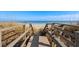 Beach access through wooden stairs and wooden railings bordered by tall dry grass on each side at 1417 S Ocean Blvd. # 202, Surfside Beach, SC 29575