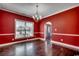 Dining room with hardwood flooring, chandelier, white trim, and bright red walls at 1585 Brookgreen Dr., Myrtle Beach, SC 29577