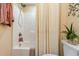 Bright bathroom with shower-tub combo featuring neutral walls, a patterned shower curtain, and decorative plants at 233 Banbury Ln. # 302, Little River, SC 29566