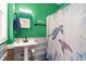 Bright bathroom with green walls, a pedestal sink, and shower featuring a colorful turtle-themed curtain at 311 51St Ave. N, North Myrtle Beach, SC 29582