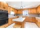 A bright eat-in kitchen features wood cabinets, an island with seating, stainless steel appliances, and a window at 311 51St Ave. N, North Myrtle Beach, SC 29582