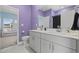 Bright bathroom features a double vanity with white cabinetry and contrasting lilac painted walls at 4092 Bayhill St., Myrtle Beach, SC 29579