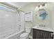 Well-lit bathroom features white tile, a vanity, an oval mirror, and tub-shower combo at 9840 Conifer Ln., Murrells Inlet, SC 29576