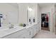 Modern bathroom featuring double sinks, white cabinets, and a walk-in closet for ample storage at 115 Galil Dr. # B, Myrtle Beach, SC 29579