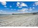 Sandy beach with the pier in view on a clear, sunny day at 126 N Waccamaw Dr. # 203, Garden City Beach, SC 29576