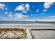 Beautiful beach view showing a sandy beach with ocean waves and a fishing pier under a blue cloudy sky at 126 N Waccamaw Dr. # 203, Garden City Beach, SC 29576
