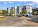 Condo building with palm trees and parking, highlighting Unit C-103 with blue accents and a private balcony at 1500 Cenith Dr. # C-103, North Myrtle Beach, SC 29582