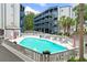 Community pool surrounded by condos with lounge chairs and tables at 1500 Cenith Dr. # C-103, North Myrtle Beach, SC 29582