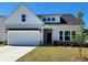 Charming single-story home boasts a two-car garage and manicured front lawn under a bright blue sky at 323 Dunlin Pl, Conway, SC 29526
