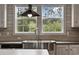 Close-up of a stainless steel farmhouse sink with a modern faucet and natural light from the window at 3685 Nichols Hwy., Aynor, SC 29511