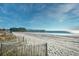 Sandy beach with a distant view of a pier, vegetation, and a clear blue ocean at 4717 Cobblestone Ln. # B3, Myrtle Beach, SC 29577