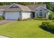 Charming brick home featuring an attached garage, manicured lawn, and colorful flower beds enhancing curb appeal at 4856 Bermuda Way N, Myrtle Beach, SC 29577