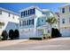 Charming three-story home with a two car garage, lush landscaping, and a blue exterior paint job at 4934 Salt Creek Ct., North Myrtle Beach, SC 29582