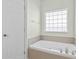 Bright bathroom showcasing a soaking tub beneath a window and next to a door at 606 5Th Ave. S, North Myrtle Beach, SC 29582