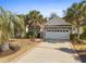Charming single-story home featuring a stone facade, two-car garage, palm trees, and a patterned concrete driveway at 606 5Th Ave. S, North Myrtle Beach, SC 29582
