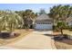 Charming single-story home featuring a stone facade, two-car garage, palm trees, and a patterned concrete driveway at 606 5Th Ave. S, North Myrtle Beach, SC 29582