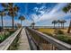 Scenic wooden walkway leading to the beach with palm trees and ocean views at 10200 Lake Shore Dr. # 16, Myrtle Beach, SC 29572