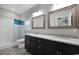 Bathroom featuring granite countertops, dual sinks, framed mirrors, and a tub with a blue patterned shower curtain at 1107 Haden Place, Calabash, NC 28467