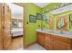 Bathroom featuring wood vanity with double sinks, green walls, and a view into an adjacent bedroom at 136 Da Gullah Way # A, Pawleys Island, SC 29585