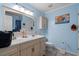 Bathroom featuring double vanity sinks, a mirror, and blue walls, with a toilet and cabinet at 1917 Candy Ln., Surfside Beach, SC 29575