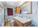 A cozy bathroom features a vanity with a framed mirror, light blue walls, and a shower with a patterned curtain at 1917 Candy Ln., Surfside Beach, SC 29575