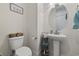 Half-bath with pedestal sink, round mirror, toilet, and decorative shelves in a well-lit space at 2794 Howard Ave. # D, Myrtle Beach, SC 29577