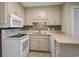 A well-lit kitchen features white appliances, tile backsplash, and ample storage in this tidy and efficient space at 306 74Th Ave. N # 105, Myrtle Beach, SC 29572