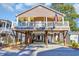 Inviting two-story home featuring a charming porch, sturdy pilings, and a cozy outdoor entertainment space at 6001-O32 S Kings Hwy., Myrtle Beach, SC 29575
