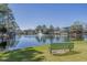 Scenic pond view featuring a fountain, green bench, and waterfront homes, creating a serene atmosphere at 6001-1479 S Kings Hwy., Myrtle Beach, SC 29575